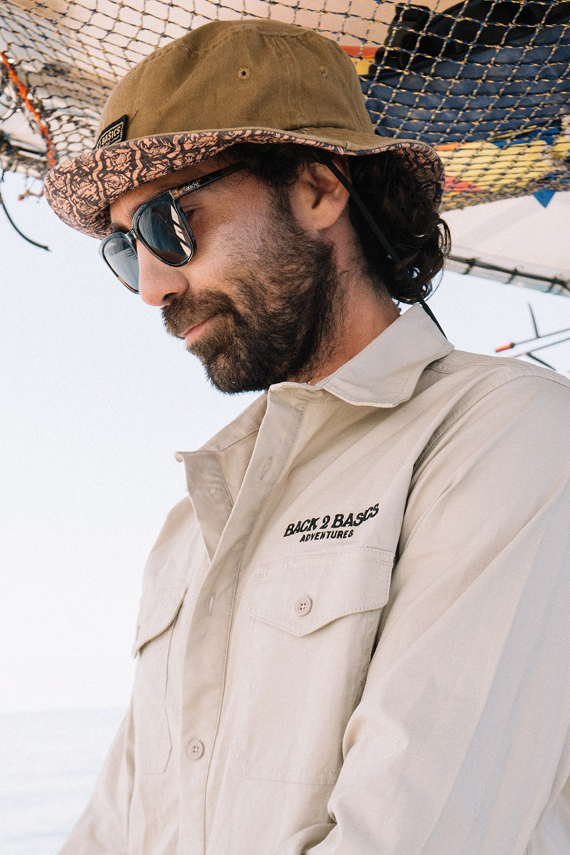 wearing a b2b grab life bucket hat in rust colour down at the beach