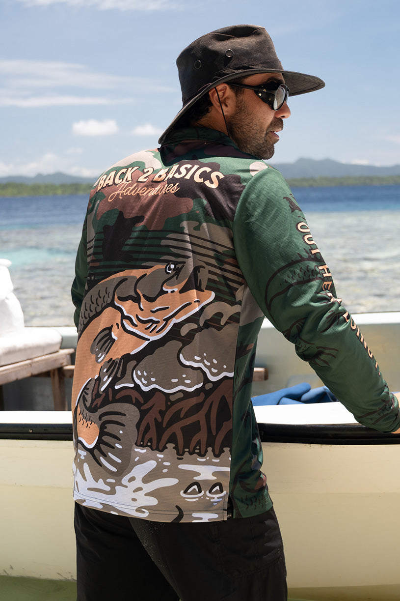 Person wearing a jacket with a tiger design and 'Back 2 Basics' branding by a body of water.