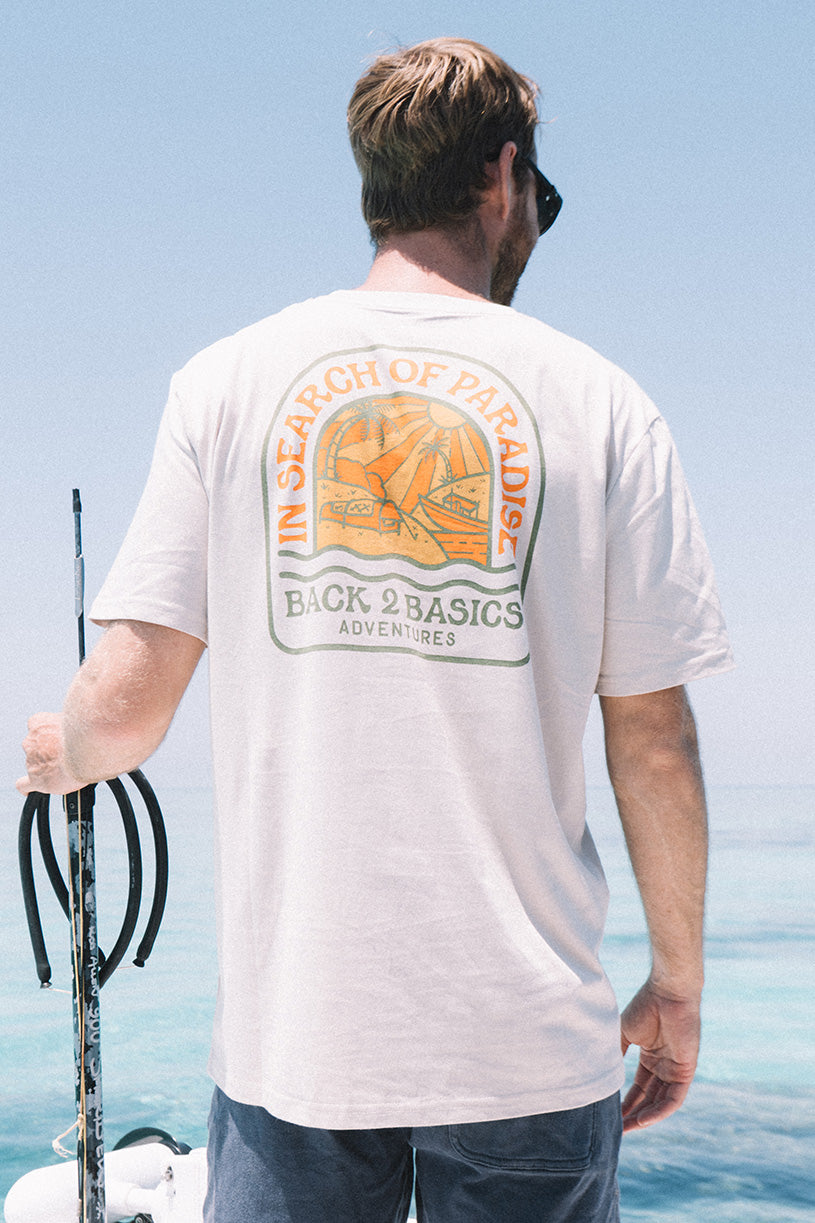 Man wearing a t-shirt with a logo and text, standing by the water.